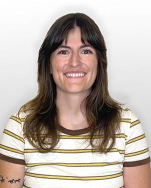 Maddie Tarara smiling in a yellow, white, and brown striped shirt against a gray background