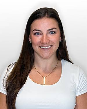 Shelagh Fluharty smiling in a white shirt against a gray background