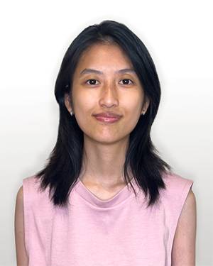 Vander Nguyen smiling in a pink shirt against a gray background