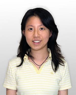 Yufan Kuang smiling in a yellow and white striped shirt against a gray background